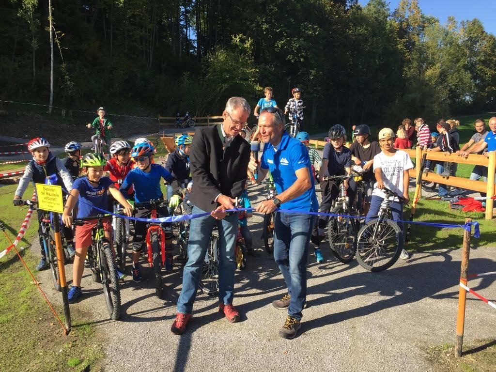 Bürgermeister Matthias Jokisch, links, und Michael Maier bei der offiziellen Eröffnung des neuen Bikeparks. Die Kids im Hintergrund in Startposition. Foto: www.toponmountain.com