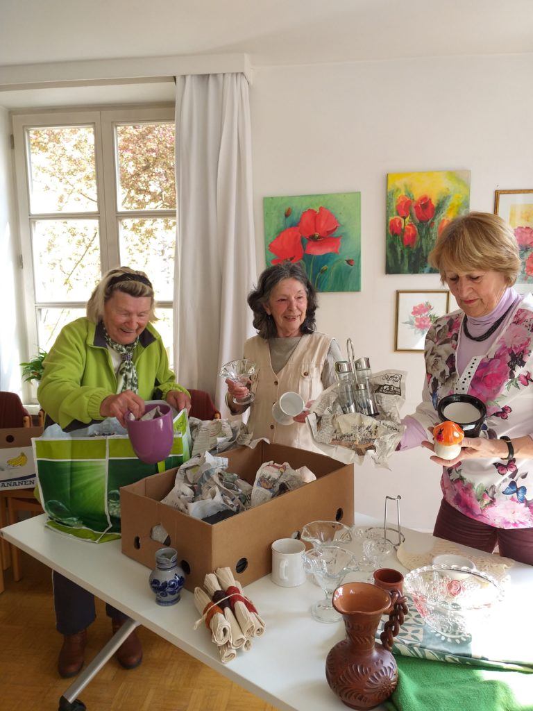 Für den Geschirrmarkt „Aufdeckt is!“ packen die ehrenamtlichen Helferinnen der Caritas Seniorenbegegnungsstätte Rosenheim Erika Kirchner, Helga Hadamek und Dorothea Ebert-Lapp Geschirr aus. Jeder Griff ist eine Überraschung.