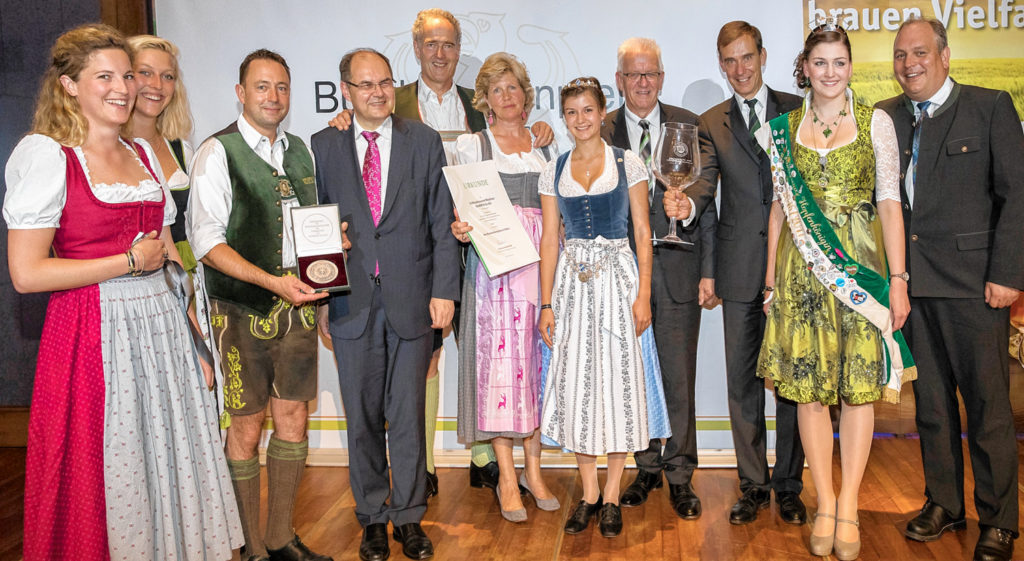 Bundesehrenpreis in Silber für Schlossbrauerei Maxlrain: Bundesminister Christian Schmidt überreicht zusammen mit DLG-Präsident Carl-Albrecht Bartmer in Anwesenheit des baden-württembergischen Ministerpräsidenten Winfried Kretschmann, der bayerischen Bierkönigin Lena Hochstraßer und der Hallertauer Hopfenkönigin Sabrina Schmalhofer Medaille und Urkunde sowie den DLG-Jubiläumspokal an die Preisträger. Foto: DLG