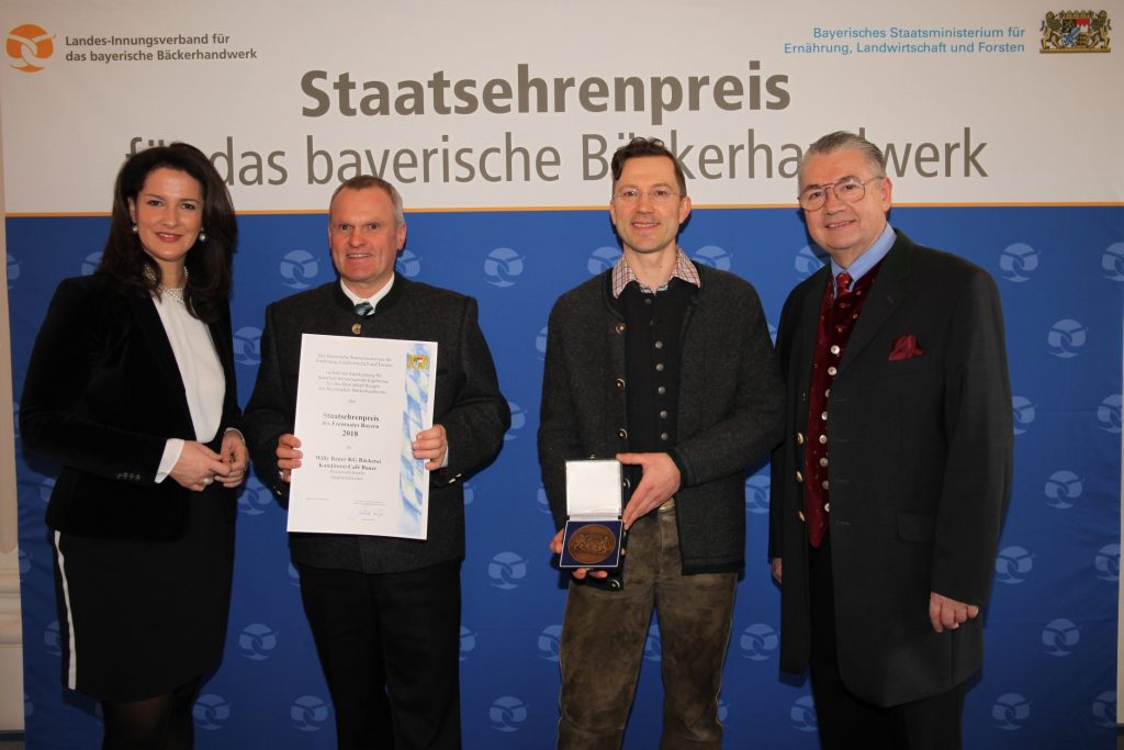 Ministerin Michaela Kaniber, links, sowie Landesinnungsmeister Heinz Hoffmann, rechts, gratulieren Alois Heinzinger, Mitte links, und Christian Bauer, Mitte rechts, zum Staatsehrenpreis.